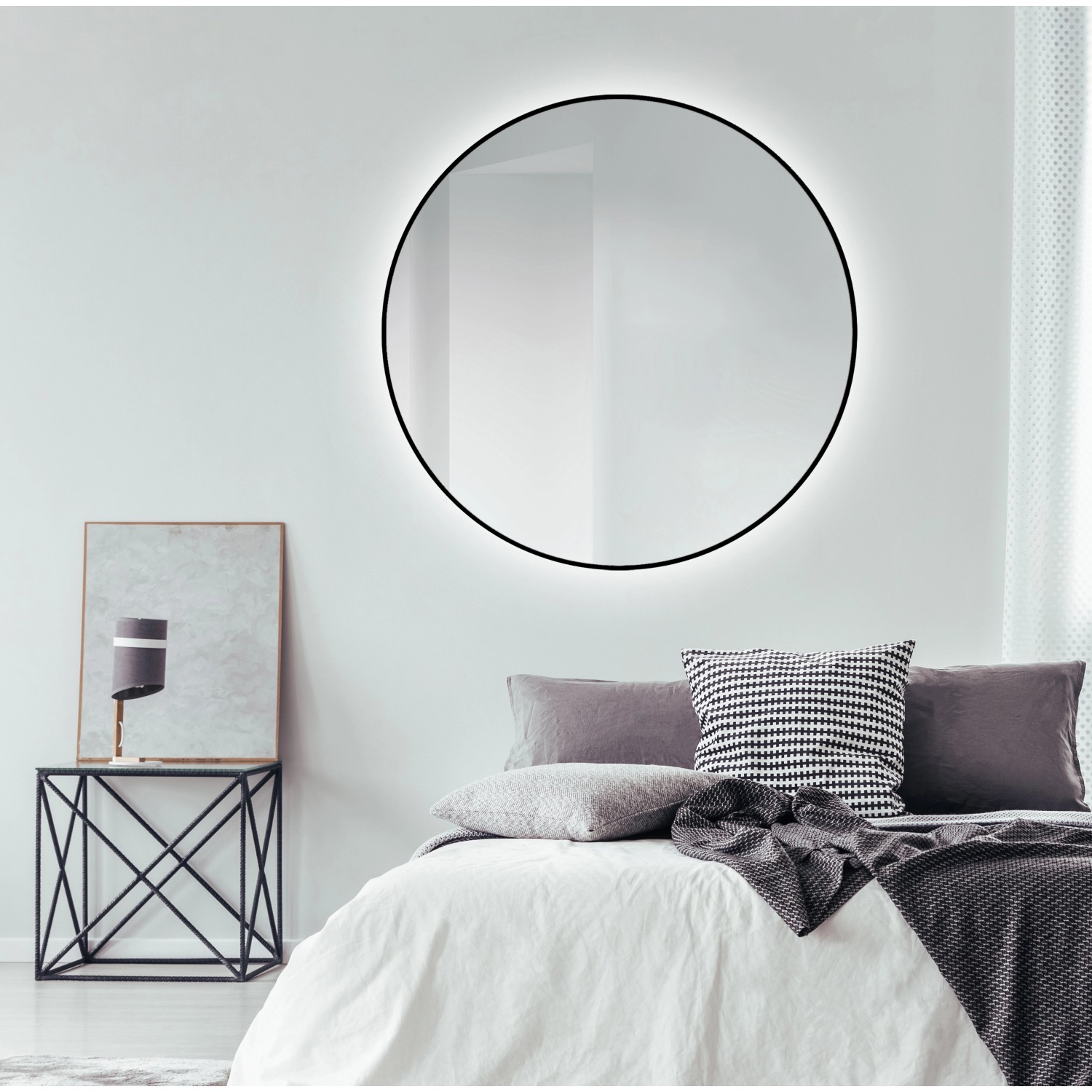 Runder DSK Design LED-Lichtspiegel Silver Globo, Ø 120 cm, mit schwarzem Rahmen an Schlafzimmerwand.
