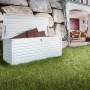 Weiße Biohort Freizeitbox 180 im Garten, geöffnet mit Kissen. Universalbox aus Metall mit Zylinderschloss.