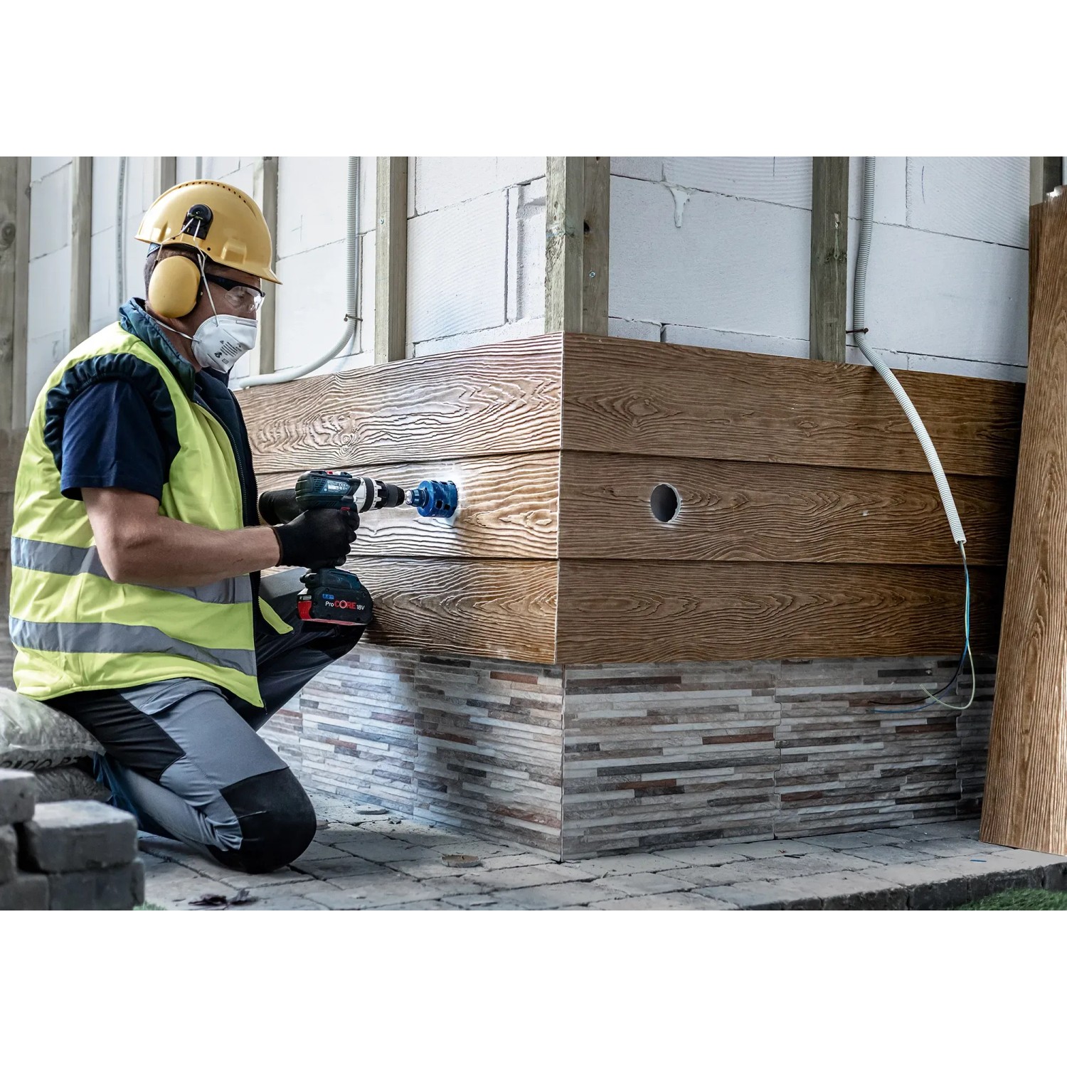 Handwerker bohrt Loch mit Bosch Expert Lochsäge Tough Material Ø 51 mm in Holzverkleidung.
