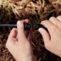 Hände verbinden schwarzes Verlängerungskabel für Philips Hue Gartenstrahler. Einfache Niedervolt-Installation im Garten.