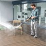 Mann reinigt Gartenstuhl mit Kärcher Universalreiniger RM 555 und Hochdruckreiniger.