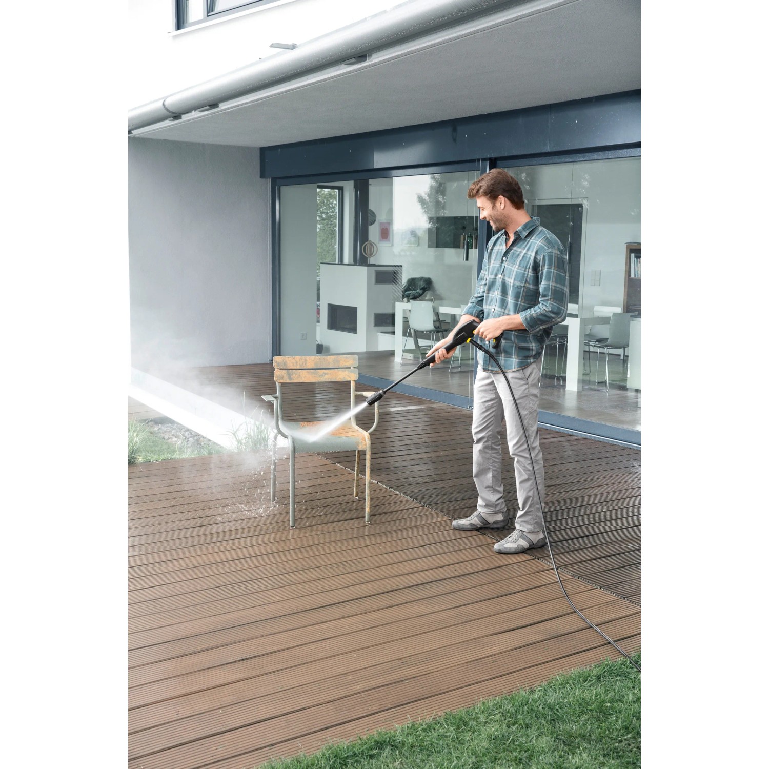Mann reinigt Gartenstuhl mit Kärcher Universalreiniger RM 555 und Hochdruckreiniger.