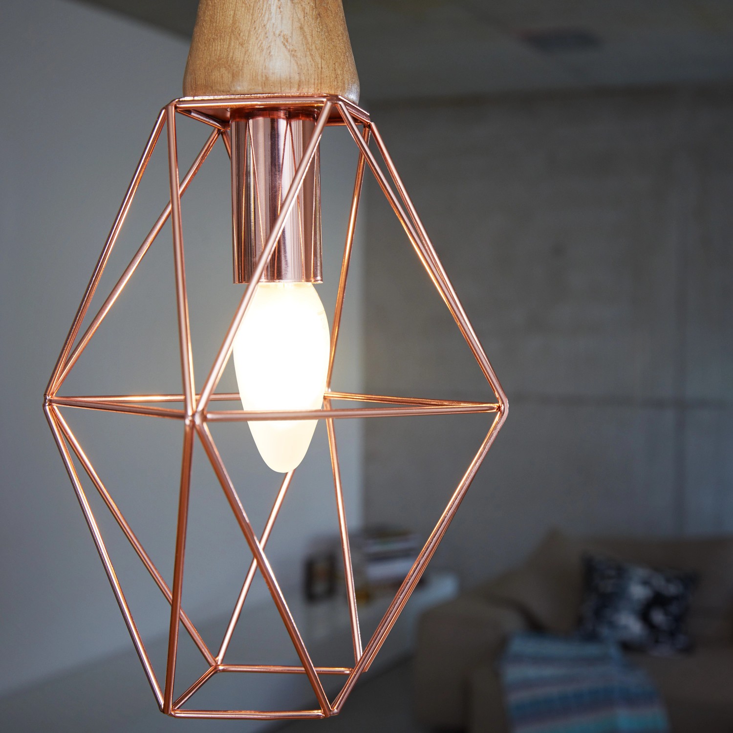 Osram E14 LED-Lampe in Kerzenform, 5,5 W, warmweiß, in Kupfer-Drahtgestell unter Holzaufhängung.