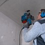 Mann bohrt mit Bosch Professional Bohrhammer GBH 2-26 in Decke. Inkl. Zubehör und L-Case.