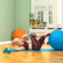 Frau macht Übungen mit blauem Sitting Ball Hocker (Petrol) auf einer blauen Matte.
