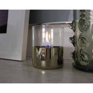 Tenderflame Tischfeuer Lilly Gold, ein Deko-Kamin aus Glas mit goldfarbenem Sockel und brennender Flamme.