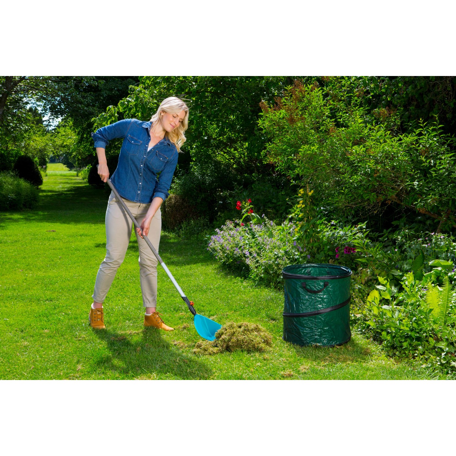 Frau rechen mit Gardena Combisystem Schaufel-Rechen Gras zusammen. Vielzweckgerät für Gartenarbeit.