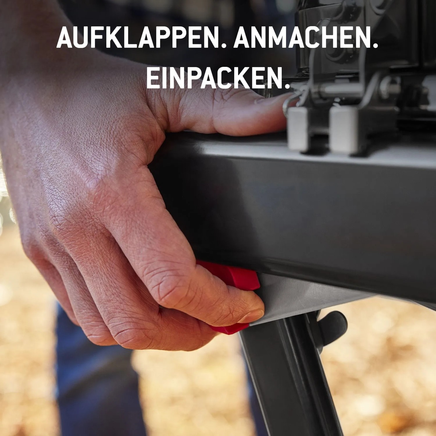 Hand betätigt roten Knopf am Weber Gasgrill Traveler Compact zum Zusammenklappen.