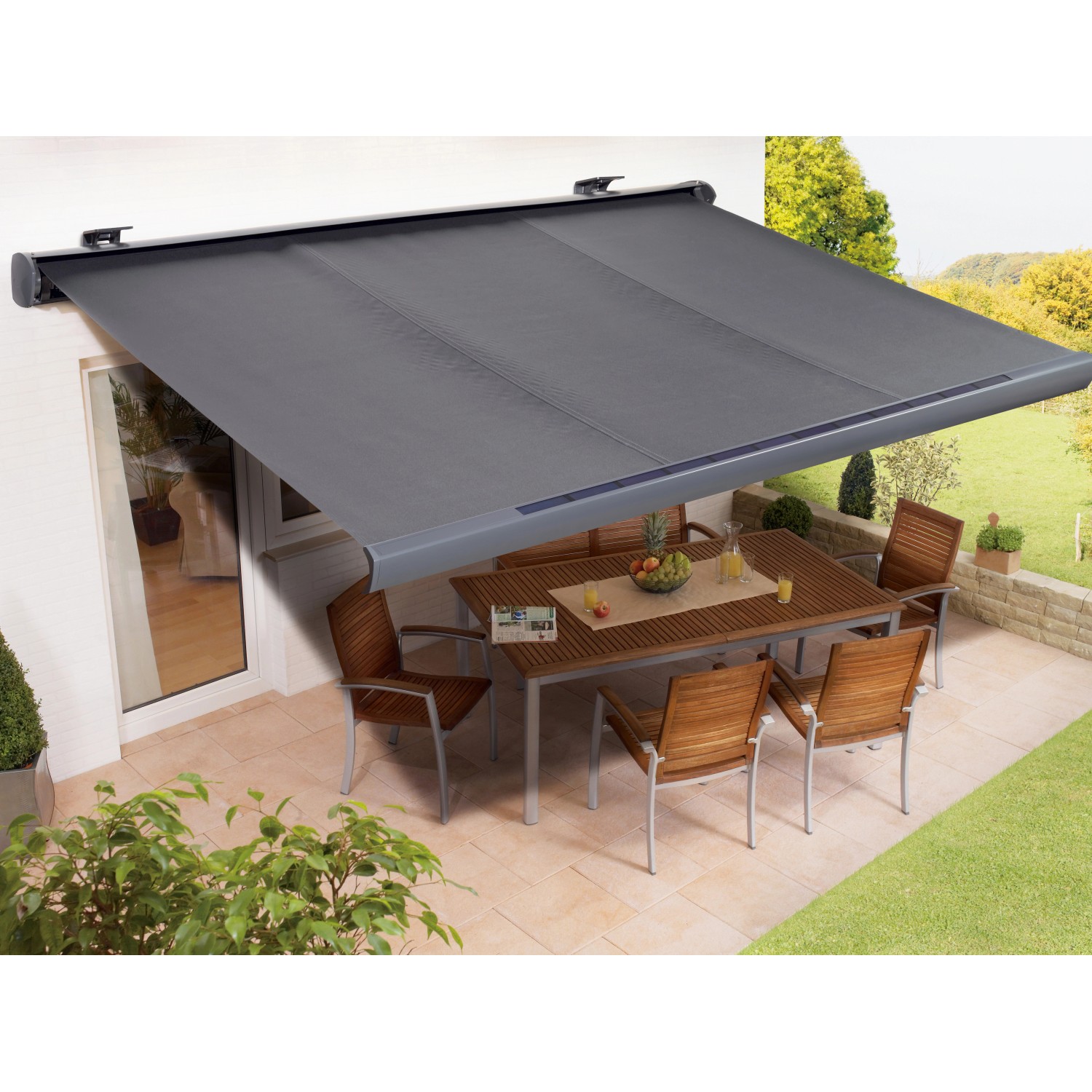 Anthrazitfarbene Kassettenmarkise Maraca 3x2 m, solarbetrieben, über einer Terrasse mit Tisch und Stühlen.