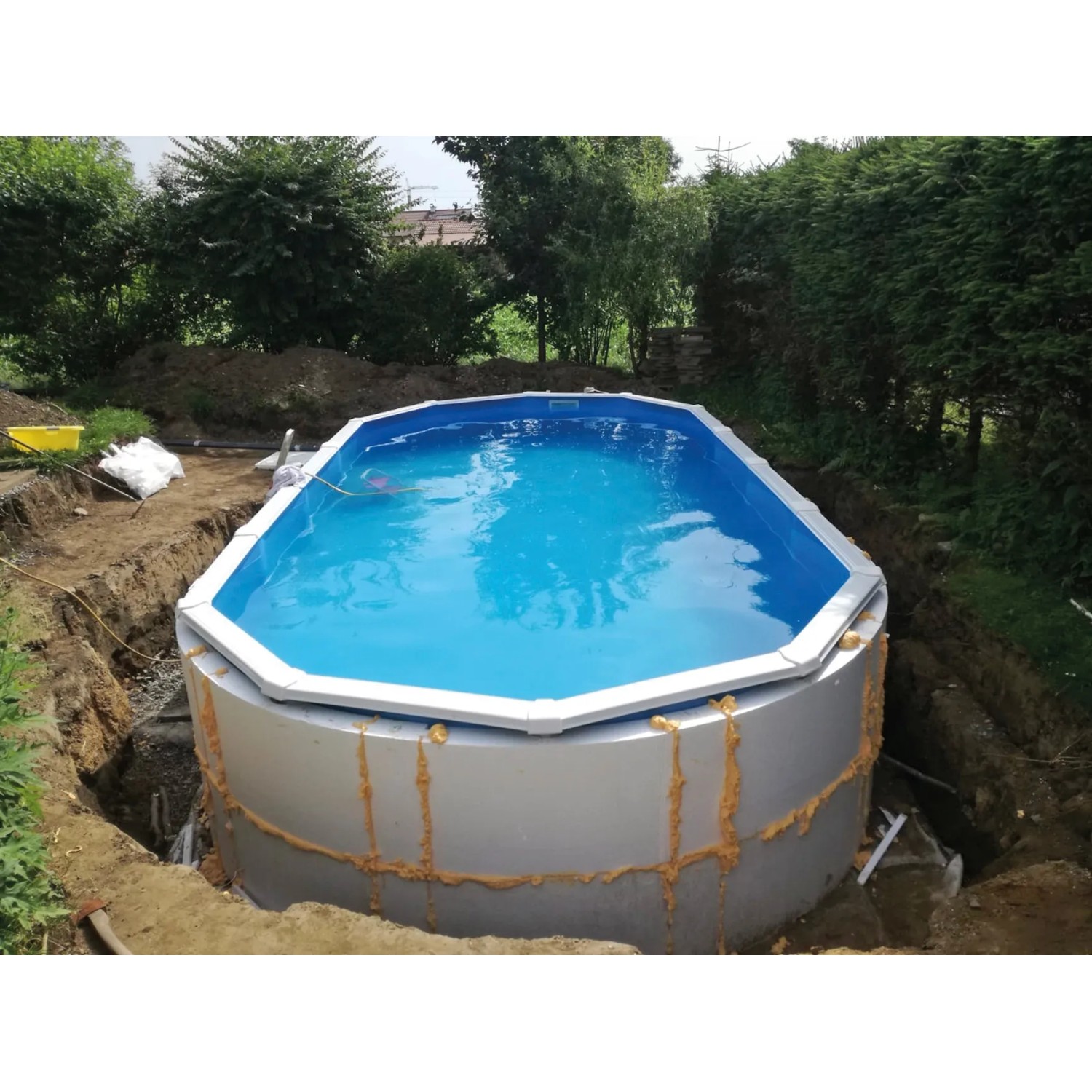 Ovaler Stahlwandpool Protector T60 (515x390x60cm) im Garten, teilweise in den Boden eingelassen.